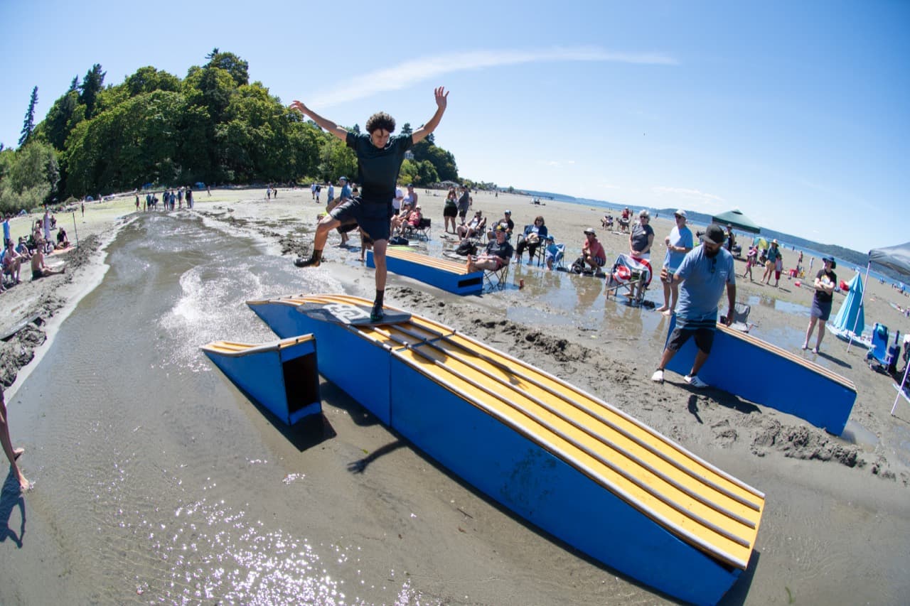 Skimboarder sliding across the Beachfest rail setup